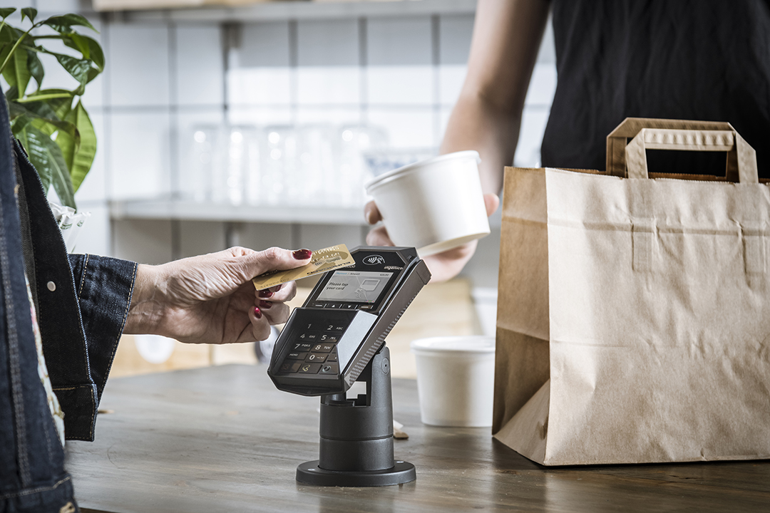 Contactless payment terminal mounted on ergonomic pole at point-of-sale counter